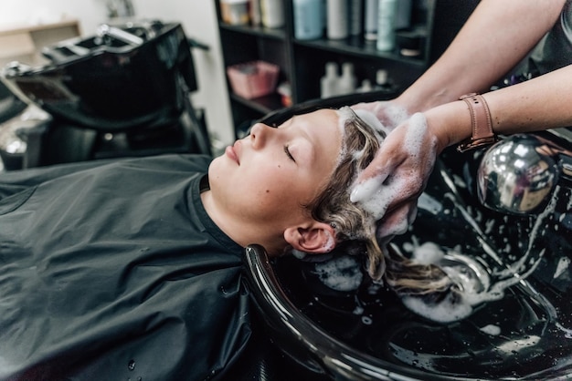 Donna che applica shampoo e massaggia i capelli del cliente Una donna che si lava i capelli da un parrucchiere