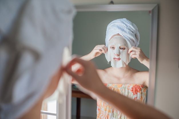 donna che applica un foglio maschera facciale