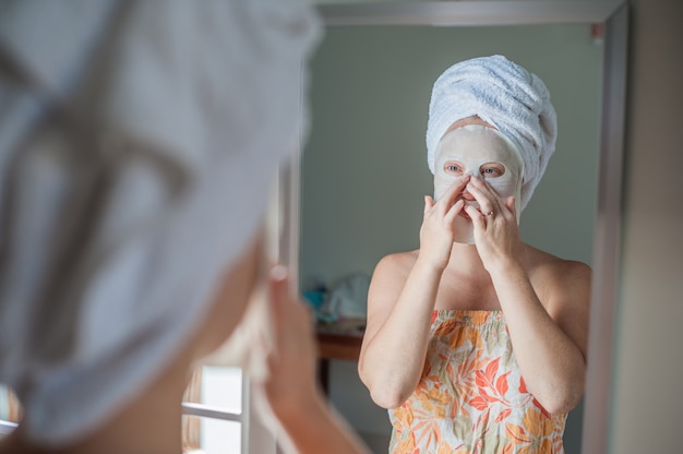 donna che applica un foglio maschera facciale