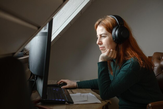 Donna che ascolta la musica in grandi cuffie vicino al computer