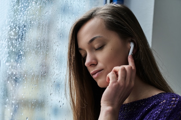 Donna che ascolta la musica vicino alla finestra