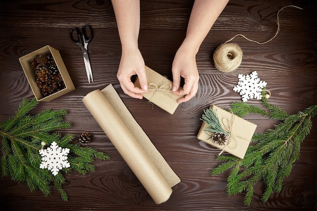 Donna che avvolge i regali di Natale sulla tavola di legno