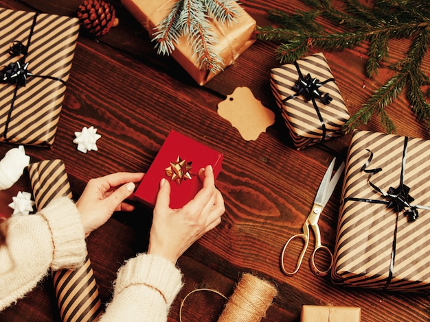 Donna che avvolge un regalo di natale su una tabella