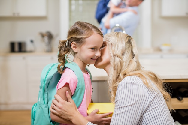 Donna che bacia sua figlia mentre va a scuola