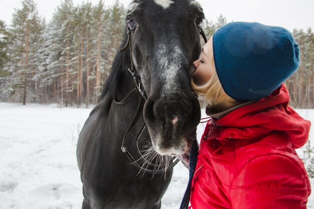 Donna che bacia un cavallo nei boschi