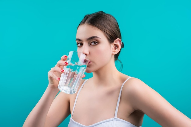 Donna che beve acqua dolce isolata sullo sfondo dello studio il modello femminile tiene un bicchiere di acqua limpida