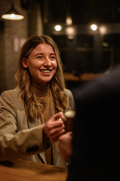 Donna che beve birra al bar con i suoi colleghi dopo il lavoro