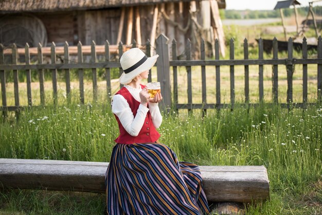 Donna che beve birra su una panchina ligo folk