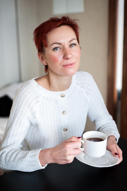 Donna che beve caffè al mattino al tavolo