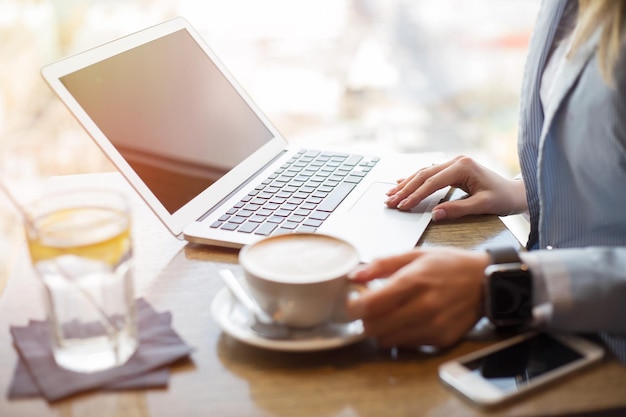 Donna che beve caffè e lavora al computer portatile