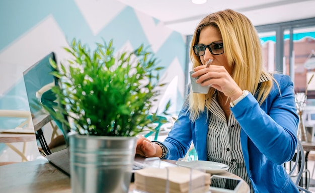 Donna che beve caffè e lavora con il laptop in una caffetteria