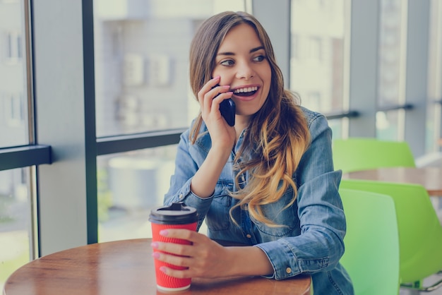 Donna che beve caffè e parla al telefono