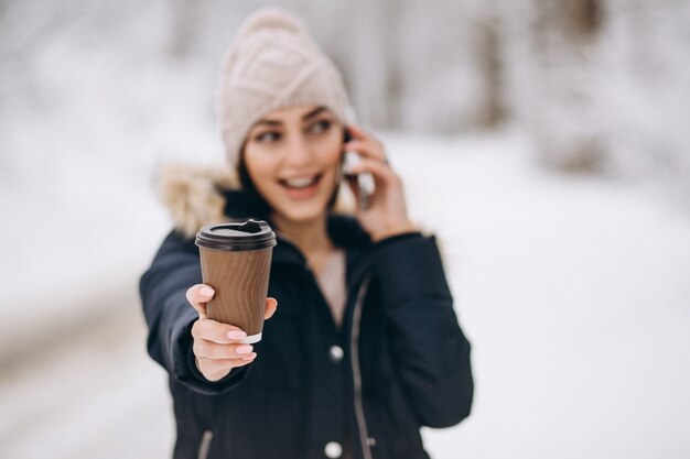 Donna che beve caffè e parlando sul phobne all&#39;esterno in inverno