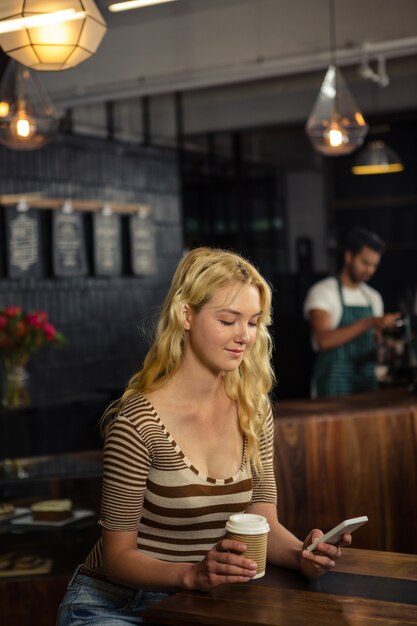 Donna che beve caffè e utilizzando smartphone