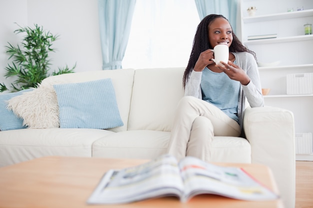 Donna che beve caffè sul divano