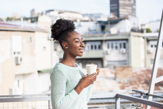 Donna che beve caffè sul suo balcone