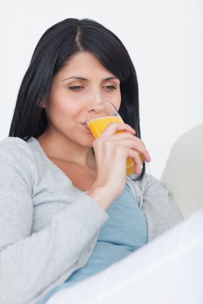 Donna che beve da un bicchiere di succo d&#39;arancia