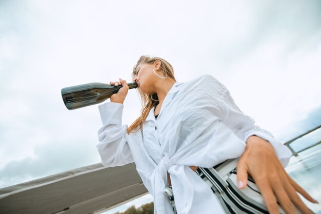 Donna che beve da una bottiglia di champagne