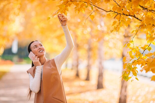 donna che beve il caffè nel parco sotto il fogliame di autunno