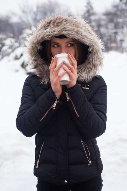 Donna che beve il suo tè o caffè caldo dalla tazza. Stagione invernale.