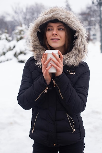 Donna che beve il suo tè o caffè caldo dalla tazza. Stagione invernale.