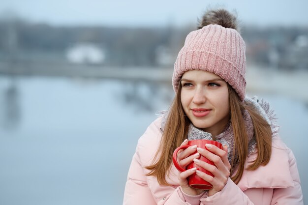 Donna che beve il tè da una tazza rossa