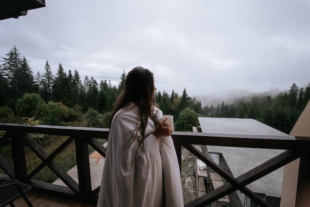 Donna che beve il tè sull'accogliente balcone di una casa di campagna