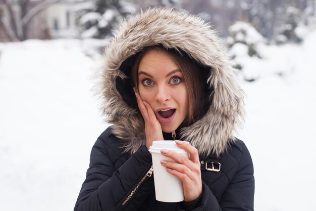 Donna che beve la sua bevanda calda dalla tazza. Stagione invernale.