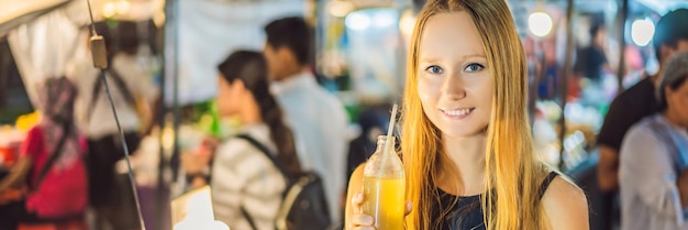 Donna che beve succo di canna da zucchero sul formato lungo banner mercato asiatico