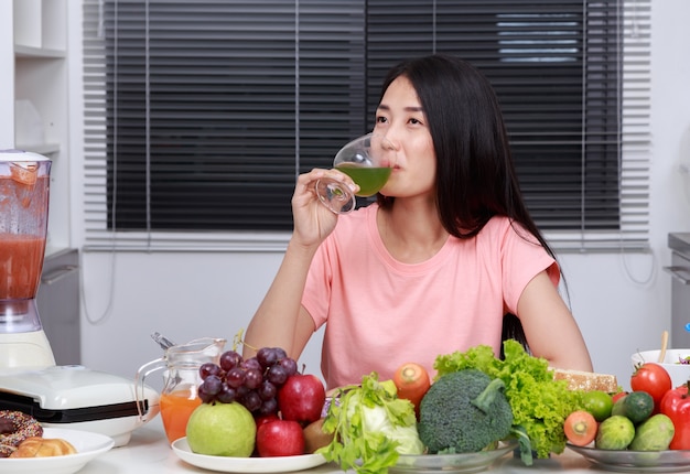 donna che beve succo di verdura in cucina