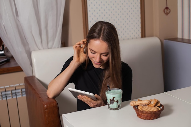 Donna che beve tè e utilizza tablet