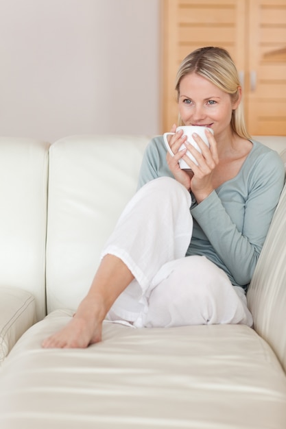 Donna che beve un sorso di caffè sul divano