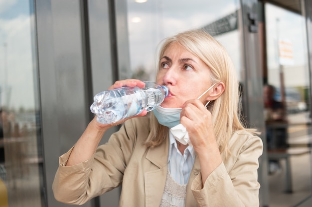 Donna che beve una bottiglia d'acqua durante la pandemia di coronavirus