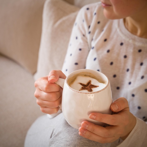 Donna che beve una tazza di caffè o tè seduta comodamente a casa Rilassatevi e riposatevi