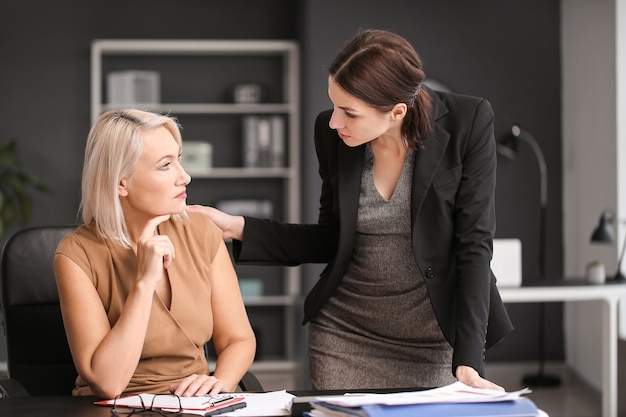 Donna che calma il suo collega maturo licenziato in ufficio