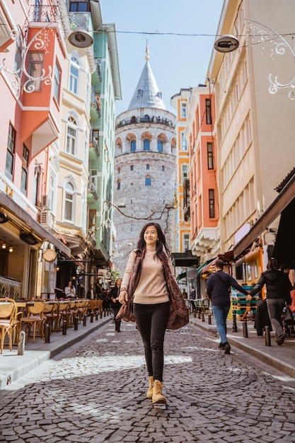 Donna che cammina attraverso un vicolo pieno di caffè e edificio storico a istanbul turchia