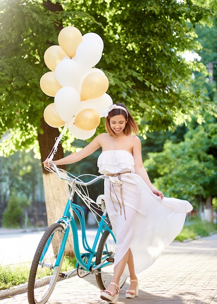 donna che cammina con biciclette d'epoca e palloncini