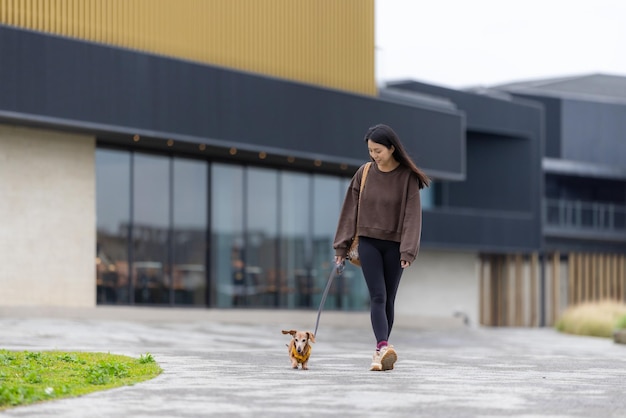 Donna che cammina con il suo cane dachshund nel parco