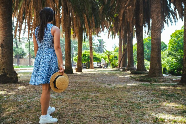 Donna che cammina dal parco di palme in abito blu. vacanze estive