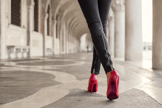 Donna che cammina in pantaloni neri e tacchi rossi