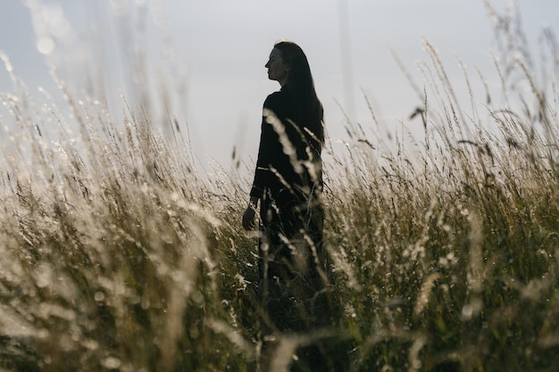 Donna che cammina in un campo di grano la sera rilassante