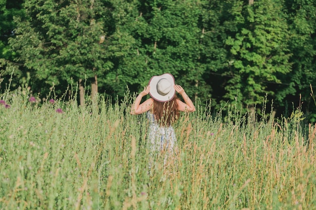 Donna che cammina in un campo in una giornata di sole estivo vista sul retro