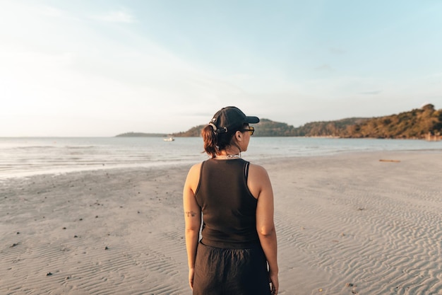 Donna che cammina lungo la spiaggia la sera