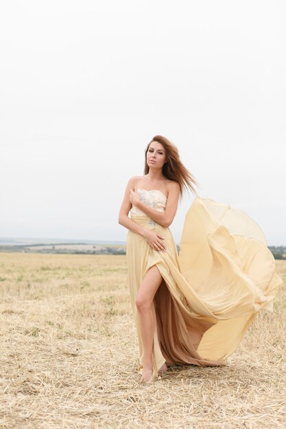 Donna che cammina nel campo di erba secca dorata. Bellezza naturale del ritratto. Bella ragazza in un campo di grano