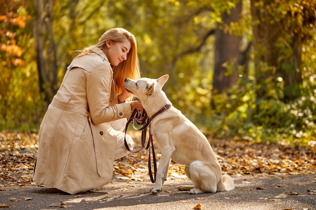 Donna che cammina nella foresta di autunno con il compagno di cane