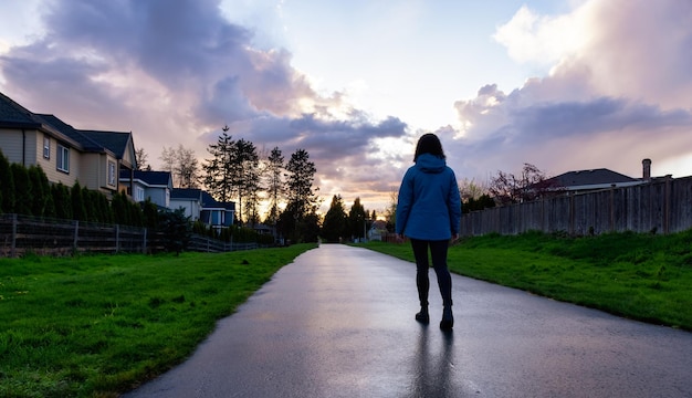 Donna che cammina su un sentiero in un quartiere residenziale della moderna periferia della città
