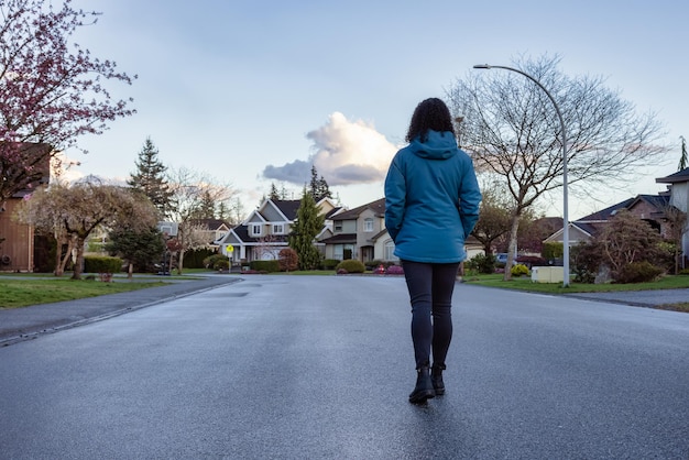 Donna che cammina su una strada in un quartiere residenziale della moderna periferia della città