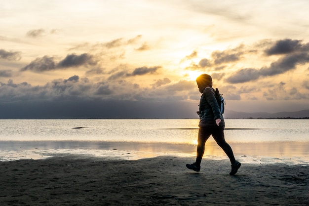 Donna che cammina sulla spiaggia al tramonto