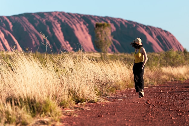 Donna che cammina sulla strada a Uluru in Australia Foto d'archivio di una donna che viaggia in Australia
