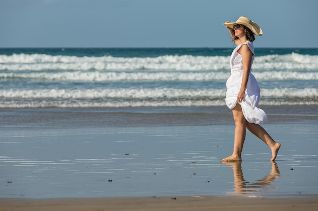 Donna che cammina vicino al mare e ammira la spiaggia